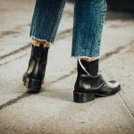person in blue denim jeans and black leather boots