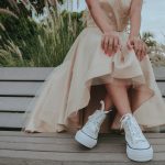 woman in white floral lace dress and white leather boots sitting on brown wooden bench