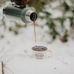 depth photo of person holding vacuum flask filling cup