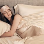 A woman lies in bed, wearing a sleep mask.