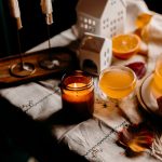 Cozy autumn table setting with lit candle and orange slices