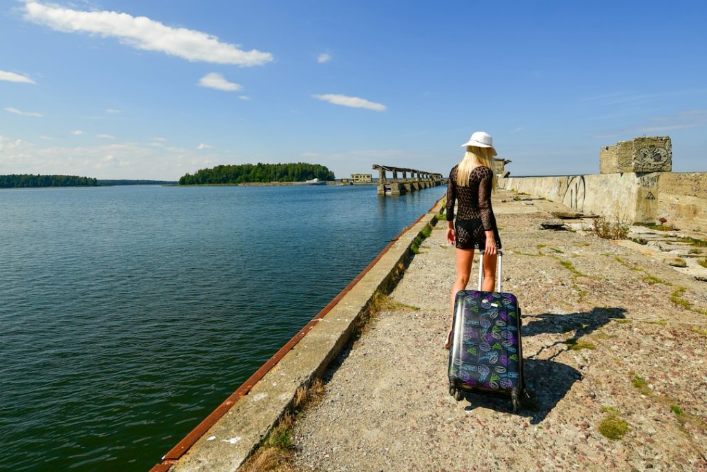 Woman with suitcase walks on a pier by the water