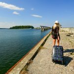 Woman with suitcase walks on a pier by the water