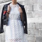 woman with coat beside cinder block wall