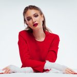 woman in red long sleeve shirt sitting on white textile