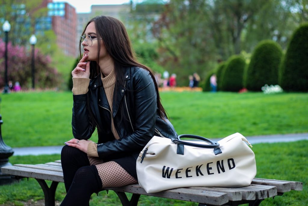 a woman sitting on a bench with a weekend bag