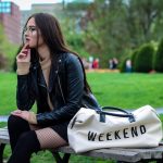 a woman sitting on a bench with a weekend bag