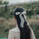 woman in white dress with white ribbon on head