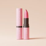 a pink lipstick with a brown cap on a pink background