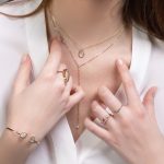 a close up of a person wearing rings and a necklace